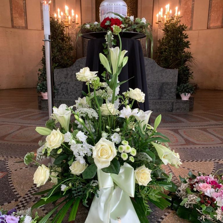 Grabgesteck Blumenarrangement in einer eleganten Trauerstätte mit Kerzen und Dekoration.