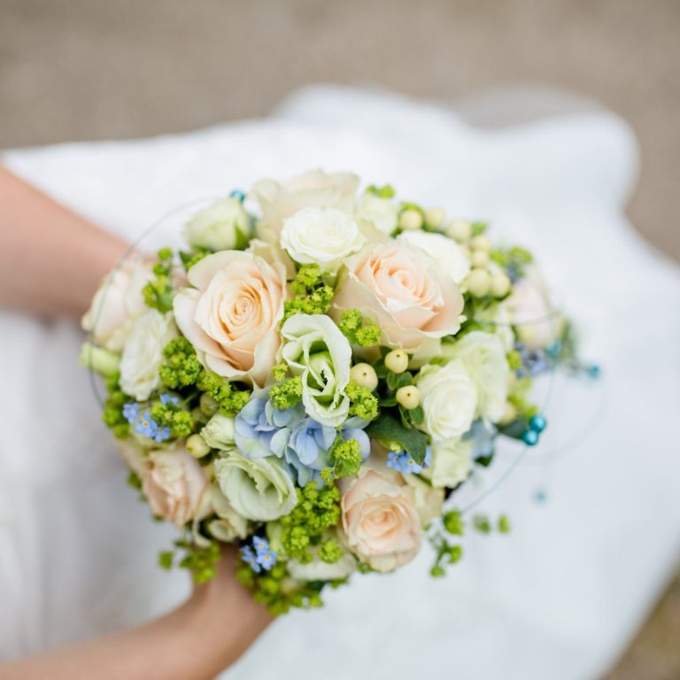 Tischschmuck Ein rustikaler Tischaufsatz aus Holz mit einer Glasvase und weißen Blumen.
